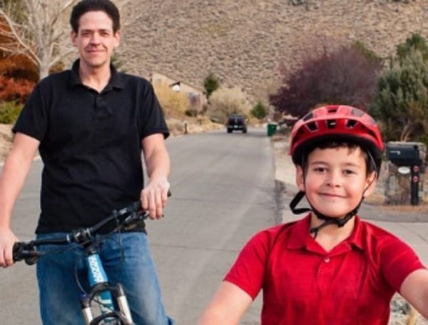 Adam Woodrum and his son, Robert, bike near their home in Carson City, Nevada, on Nov. 7. When Robert fell off his bike in July, he got stitches at Carson Tahoe Regional Medical Center. The family’s insurer initially denied the claim. (MAGGIE STARBARD FOR KHN)