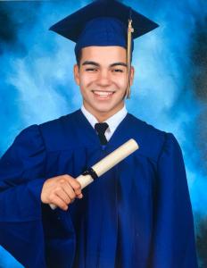 This is a picture of Matthew Rogriguez in his graduate gown and diploma.