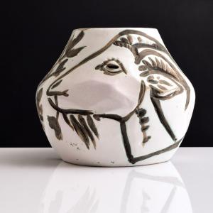 A white vase with a smiling goat in profile
