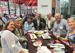 Group photo of open house guests enjoying a meal at the event. This photo features PRA"s managing partner Scott Kramer and Partner Kevin Broich