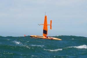 Saildrone Explorer uncrewed surface vehicle sailing in waves on a sunny day in the Pacific Ocean.